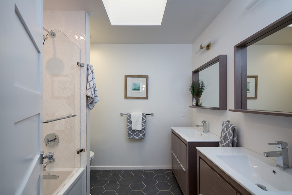 Inspiration for a large 1960s porcelain tile alcove bathtub remodel in San Francisco with flat-panel cabinets, medium tone wood cabinets, a one-piece toilet, white walls, an integrated sink and solid surface countertops