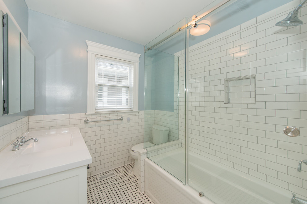 Design ideas for a medium sized classic shower room bathroom in New York with shaker cabinets, white cabinets, an alcove bath, a shower/bath combination, a two-piece toilet, white tiles, metro tiles, blue walls, porcelain flooring, an integrated sink, engineered stone worktops, multi-coloured floors and a sliding door.