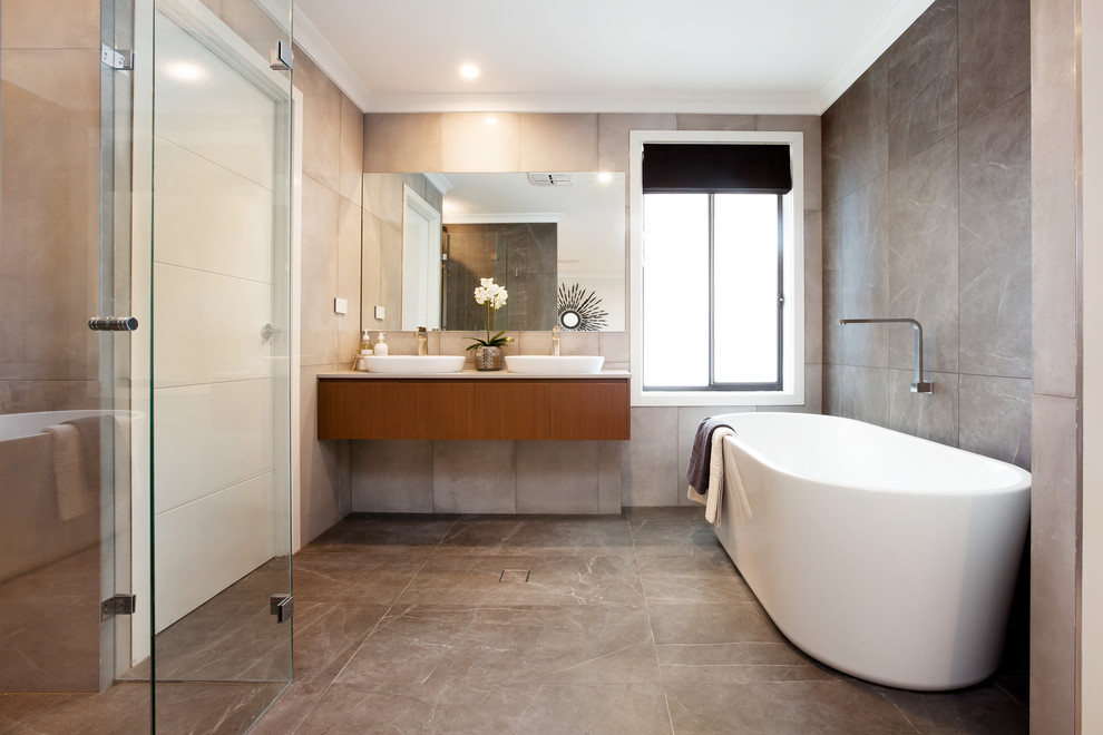 Идея дизайна: главная ванная комната в современном стиле с плоскими фасадами, фасадами цвета дерева среднего тона, отдельно стоящей ванной, душевой комнатой, серой плиткой, серыми стенами, настольной раковиной и серым полом