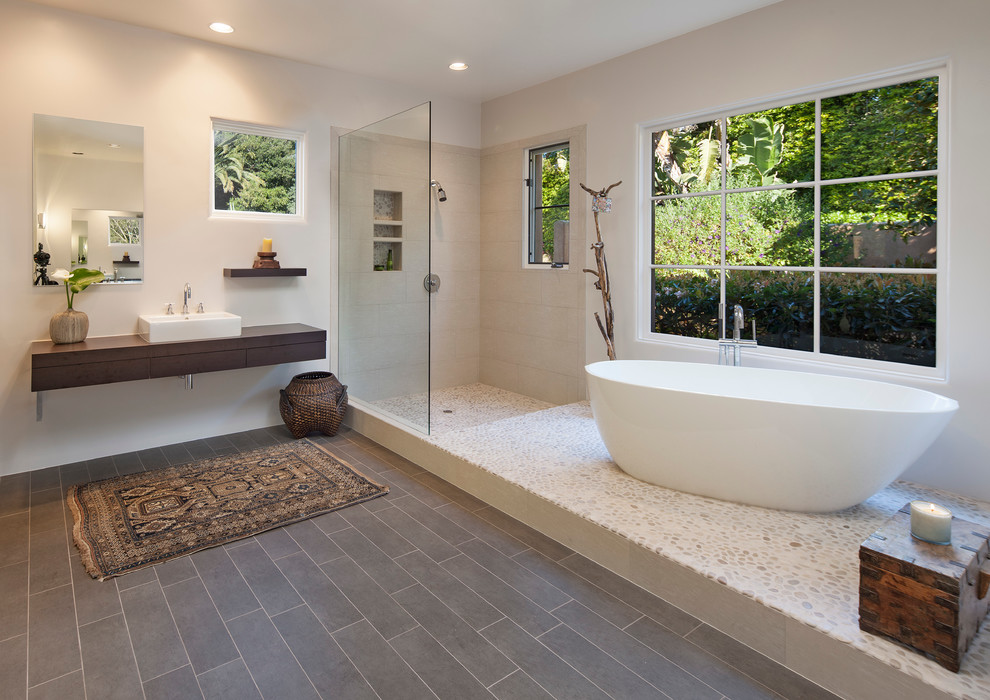 Foto på ett stort medelhavsstil brun en-suite badrum, med ett fristående badkar, en hörndusch, beige väggar, klinkergolv i keramik, ett fristående handfat, träbänkskiva, grått golv och med dusch som är öppen
