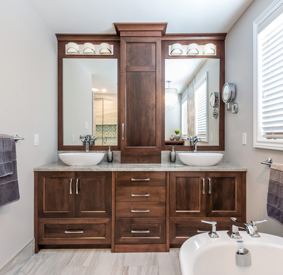 Diseño de cuarto de baño tradicional renovado con lavabo sobreencimera, armarios con paneles empotrados, puertas de armario de madera en tonos medios y bañera exenta
