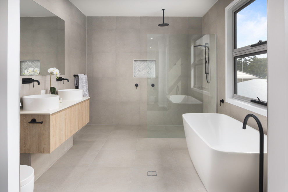 На фото: ванная комната в скандинавском стиле с плоскими фасадами, светлыми деревянными фасадами, отдельно стоящей ванной, душевой комнатой, бежевой плиткой, настольной раковиной, бежевым полом, открытым душем и белой столешницей