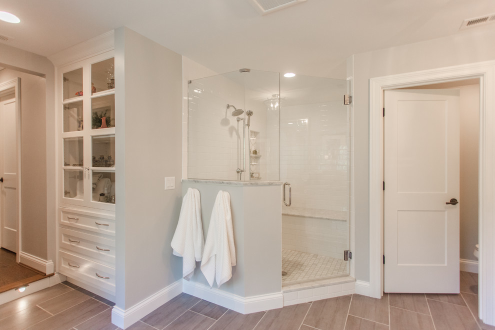 Large transitional master white tile and subway tile medium tone wood floor and brown floor bathroom photo in Cincinnati with shaker cabinets, white cabinets, gray walls, granite countertops and a hinged shower door