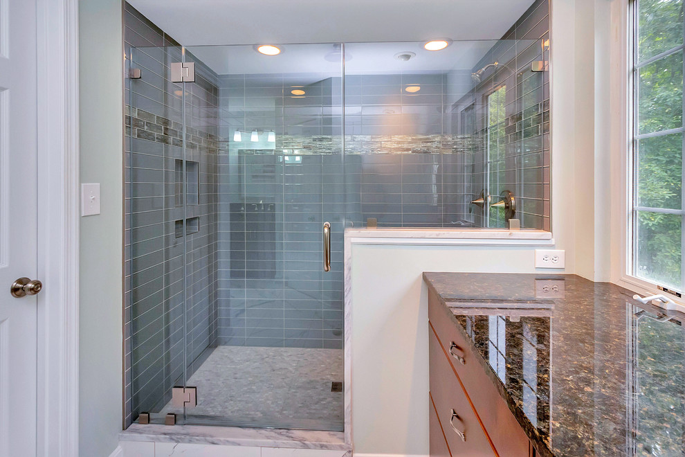 Design ideas for a large traditional ensuite bathroom in DC Metro with flat-panel cabinets, medium wood cabinets, an alcove shower, blue tiles, glass tiles, granite worktops, a hinged door, grey walls, marble flooring, white floors and a submerged sink.