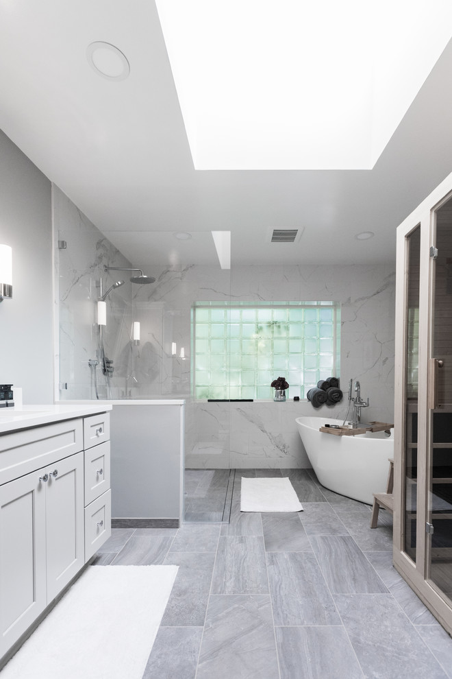 Inspiration for a medium sized classic ensuite bathroom in Seattle with freestanding cabinets, grey cabinets, a freestanding bath, a walk-in shower, a two-piece toilet, black and white tiles, porcelain tiles, grey walls, porcelain flooring, a submerged sink, solid surface worktops, grey floors, an open shower and white worktops.