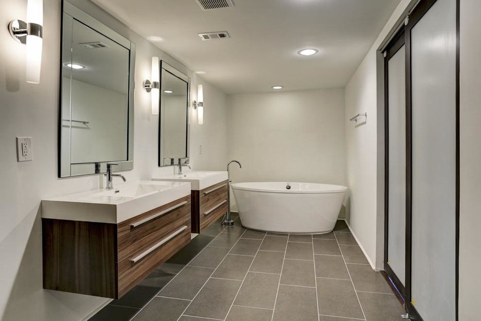 Inredning av ett modernt mellanstort en-suite badrum, med ett konsol handfat, möbel-liknande, skåp i ljust trä, bänkskiva i akrylsten, ett fristående badkar, en dusch/badkar-kombination, en toalettstol med hel cisternkåpa, grå kakel, keramikplattor, vita väggar och klinkergolv i keramik