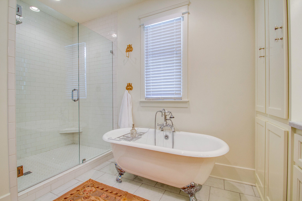 Exempel på ett klassiskt badrum, med ett undermonterad handfat, luckor med profilerade fronter, vita skåp, marmorbänkskiva, ett badkar med tassar, en dusch i en alkov, en toalettstol med separat cisternkåpa, vit kakel och keramikplattor