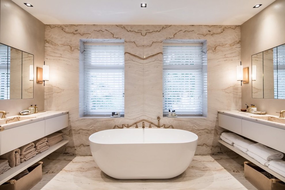 Foto de cuarto de baño principal contemporáneo con armarios con paneles lisos, puertas de armario blancas, bañera exenta, paredes beige y lavabo integrado