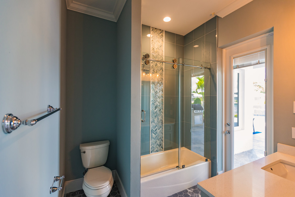 Пример оригинального дизайна: маленькая ванная комната в стиле неоклассика (современная классика) с плоскими фасадами, ванной в нише, душем над ванной, раздельным унитазом, синей плиткой, белой плиткой, керамогранитной плиткой, синими стенами, полом из мозаичной плитки, душевой кабиной, врезной раковиной, столешницей из известняка, черным полом и душем с раздвижными дверями для на участке и в саду