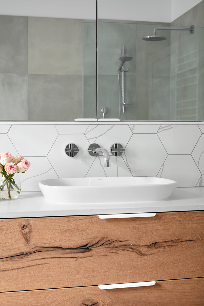 Example of a large trendy master gray tile, white tile and mosaic tile mosaic tile floor bathroom design in Melbourne with flat-panel cabinets, light wood cabinets, white walls, a vessel sink and solid surface countertops