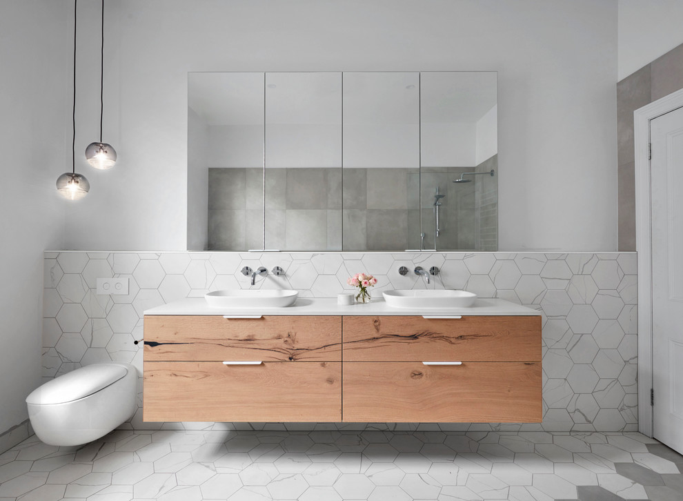 Idée de décoration pour une grande salle de bain principale design en bois clair avec un placard à porte plane, une baignoire indépendante, une douche ouverte, un carrelage gris, un carrelage blanc, mosaïque, un mur blanc, un sol en carrelage de terre cuite, une vasque et un plan de toilette en surface solide.