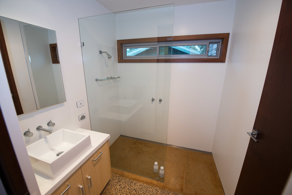 Idéer för att renovera ett mellanstort funkis en-suite badrum, med ett konsol handfat, möbel-liknande, skåp i mellenmörkt trä, bänkskiva i akrylsten, en öppen dusch, en toalettstol med hel cisternkåpa, vit kakel, glasskiva, vita väggar och betonggolv