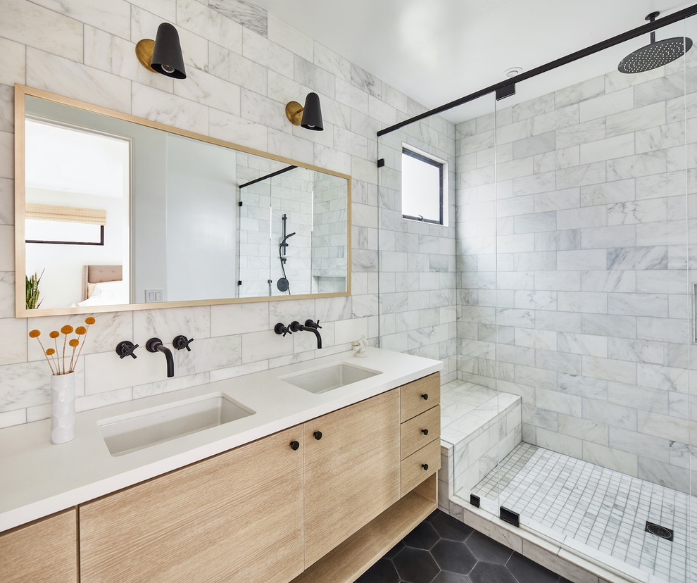 Пример оригинального дизайна: главная ванная комната среднего размера в стиле модернизм с светлыми деревянными фасадами, двойным душем, белой плиткой, мраморной плиткой, белыми стенами, полом из цементной плитки, врезной раковиной, столешницей из искусственного кварца, серым полом, душем с распашными дверями, белой столешницей, унитазом-моноблоком и плоскими фасадами