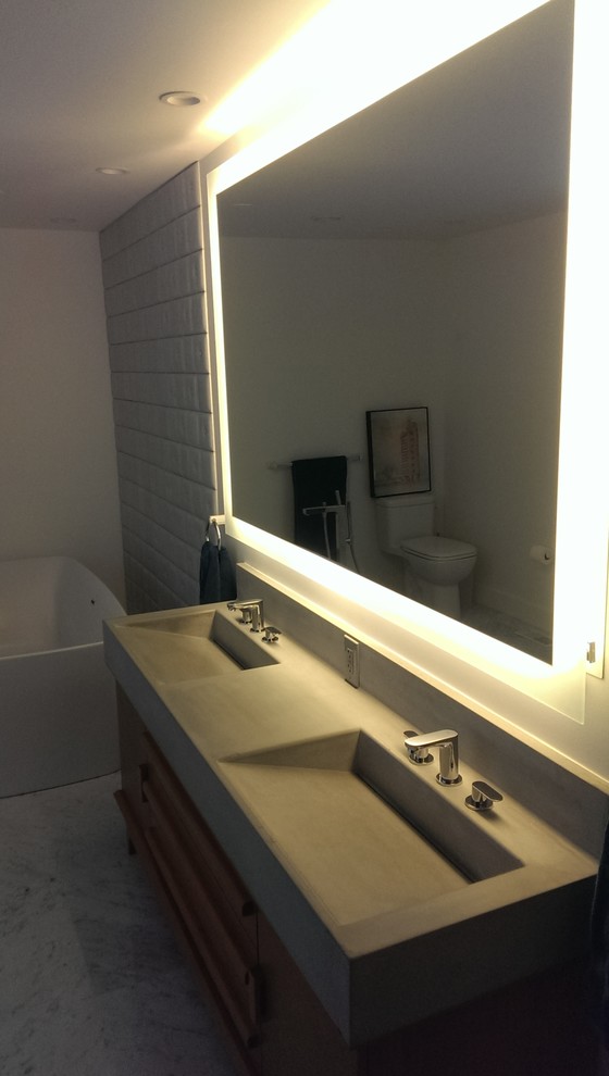 Cette image montre une salle de bain principale vintage en bois clair avec une grande vasque, un placard en trompe-l'oeil, un plan de toilette en béton, une baignoire indépendante et un mur blanc.