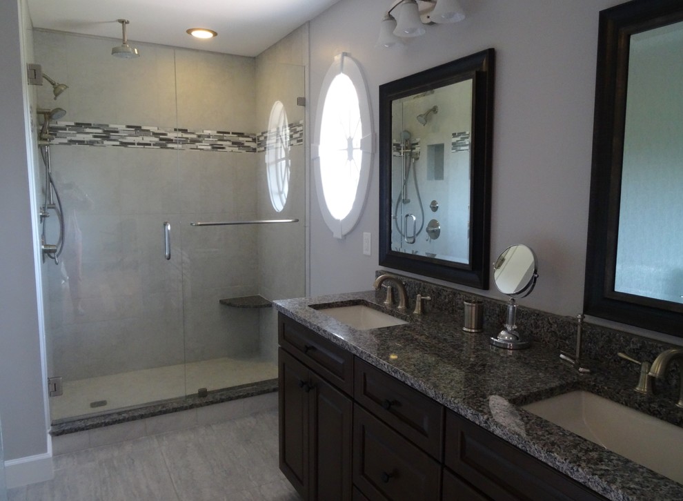 Example of a transitional master cement tile ceramic tile and gray floor freestanding bathtub design in Charlotte with shaker cabinets, dark wood cabinets, an undermount sink, granite countertops and a hinged shower door
