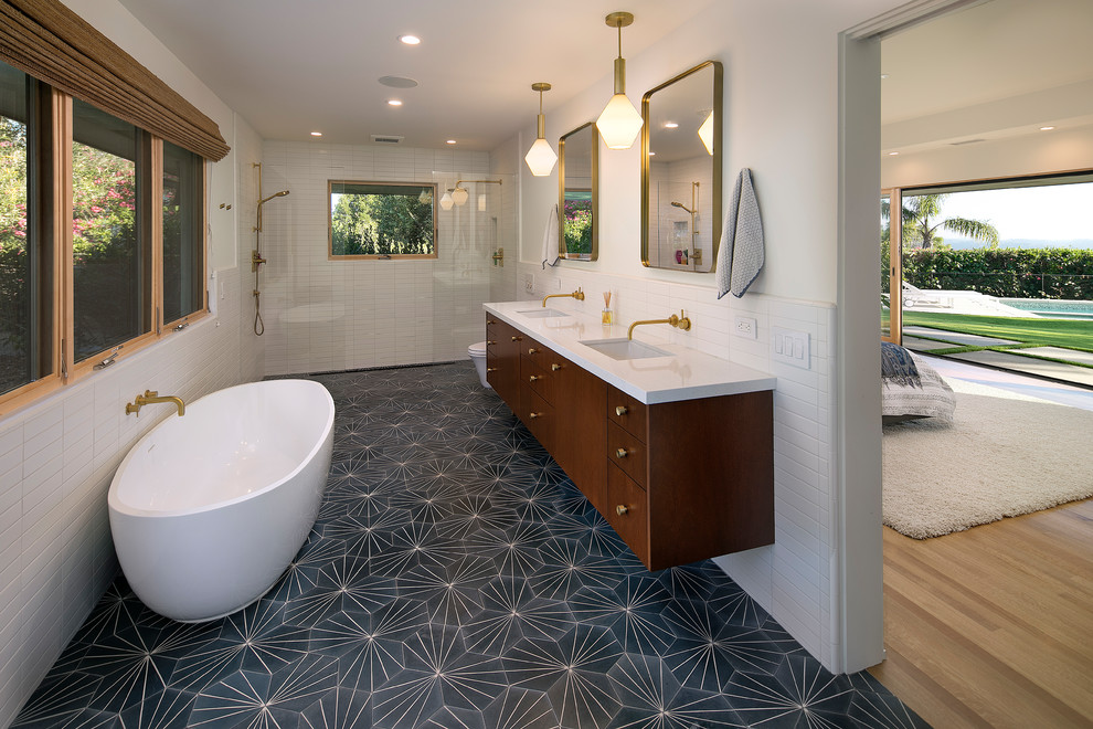 Photo of a midcentury ensuite bathroom in Santa Barbara with flat-panel cabinets, dark wood cabinets, a freestanding bath, a built-in shower, white tiles, white walls, a submerged sink, black floors, an open shower and white worktops.