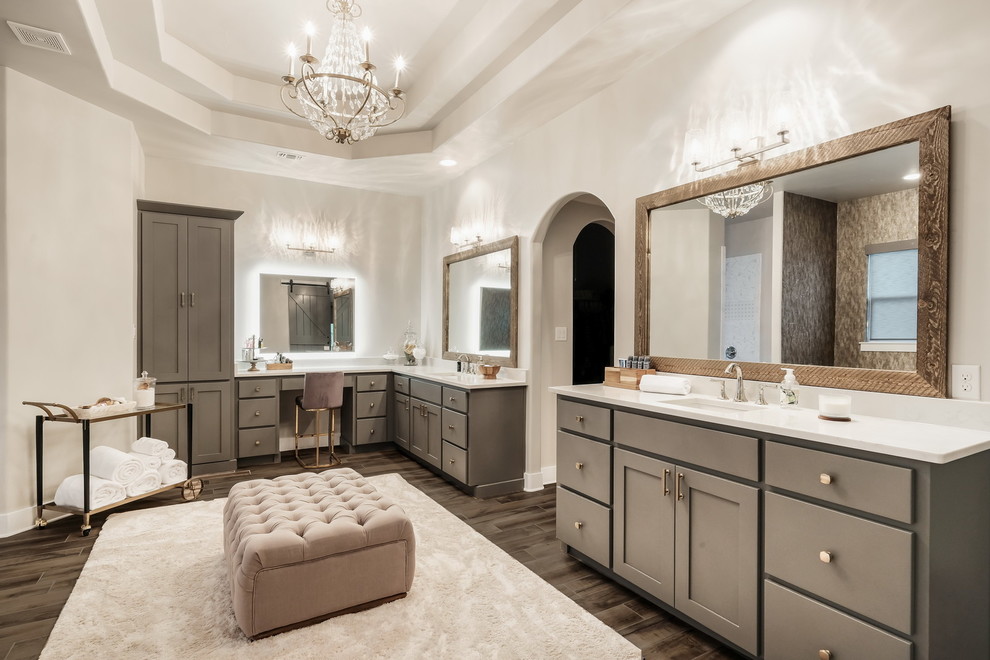 Modelo de cuarto de baño principal clásico renovado con armarios estilo shaker, puertas de armario grises, paredes blancas, suelo de madera en tonos medios, lavabo bajoencimera, suelo marrón y encimeras blancas
