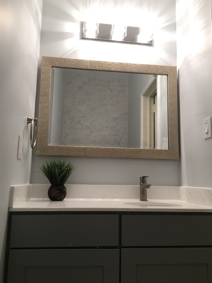 Esempio di una piccola stanza da bagno minimalista con ante in stile shaker, ante grigie, top in superficie solida e lavabo da incasso