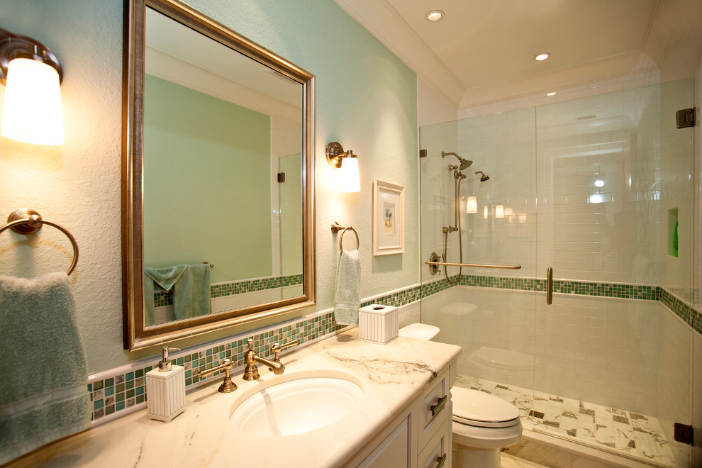 タンパにある高級な中くらいなコンテンポラリースタイルのおしゃれなバスルーム (浴槽なし) (レイズドパネル扉のキャビネット、白いキャビネット、アルコーブ型シャワー、青いタイル、緑のタイル、マルチカラーのタイル、モザイクタイル、緑の壁、大理石の床、オーバーカウンターシンク、大理石の洗面台) の写真