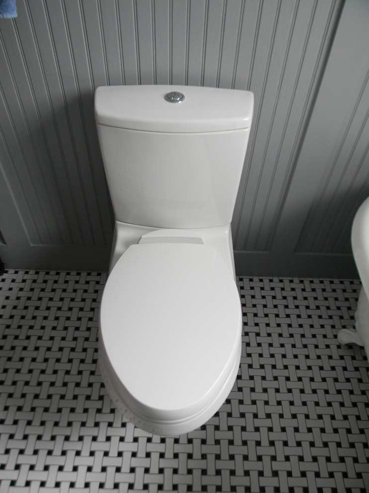 Example of a small classic 3/4 marble floor and multicolored floor freestanding bathtub design in Atlanta with recessed-panel cabinets, black cabinets, a one-piece toilet, blue walls, an undermount sink and marble countertops