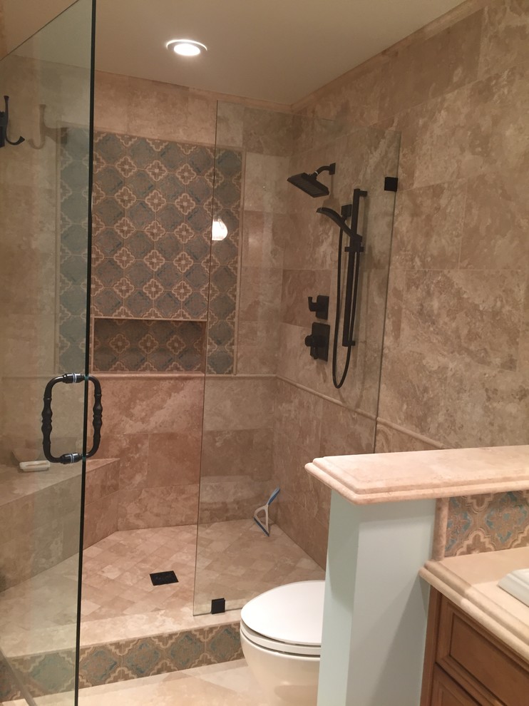 Inspiration for a medium sized mediterranean shower room bathroom in Los Angeles with raised-panel cabinets, medium wood cabinets, an alcove shower, a one-piece toilet, beige tiles, limestone tiles, blue walls, limestone flooring, a built-in sink, limestone worktops, beige floors and a hinged door.