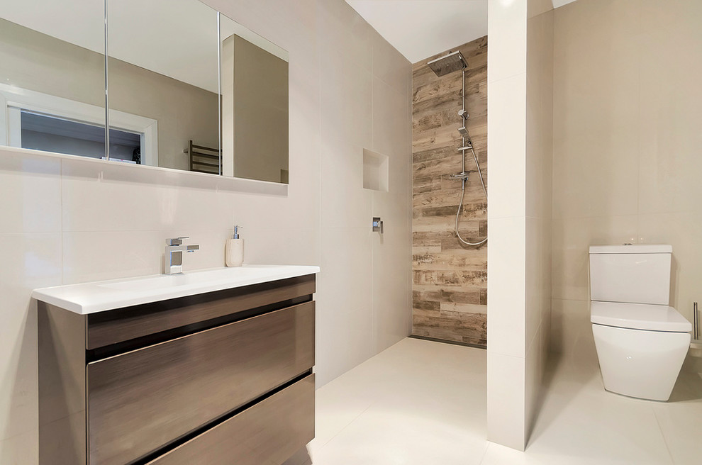 Идея дизайна: ванная комната среднего размера в современном стиле с плоскими фасадами, темными деревянными фасадами, ванной в нише, открытым душем, раздельным унитазом, бежевой плиткой, керамогранитной плиткой, бежевыми стенами и раковиной с несколькими смесителями