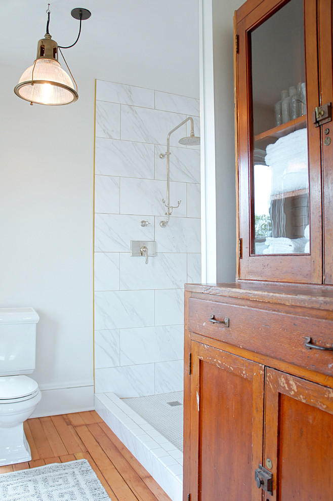Foto på ett mellanstort lantligt en-suite badrum, med möbel-liknande, skåp i slitet trä, en dusch i en alkov, en toalettstol med separat cisternkåpa, flerfärgad kakel, porslinskakel, vita väggar, mellanmörkt trägolv, ett fristående handfat och dusch med duschdraperi