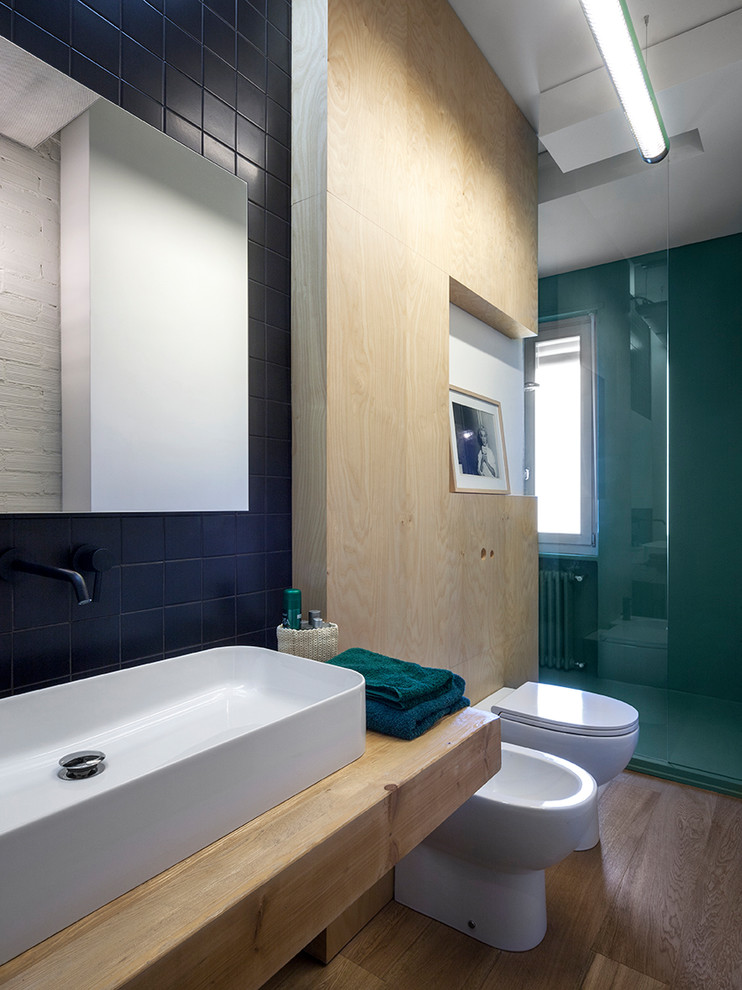 Ispirazione per una stanza da bagno industriale con doccia ad angolo, bidè, piastrelle nere, pareti verdi, lavabo a bacinella, top in legno, pavimento marrone, porta doccia scorrevole e top beige