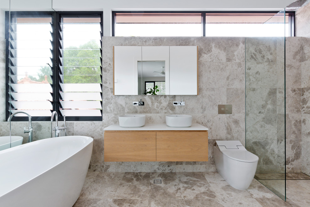 Example of a minimalist gray tile gray floor and double-sink freestanding bathtub design in Sydney with flat-panel cabinets, medium tone wood cabinets, a vessel sink, white countertops and a floating vanity