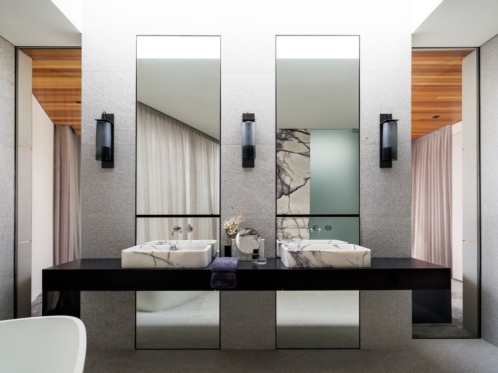 シドニーにあるコンテンポラリースタイルのおしゃれなマスターバスルーム (黒いキャビネット、置き型浴槽、グレーの壁、ベッセル式洗面器、グレーの床) の写真
