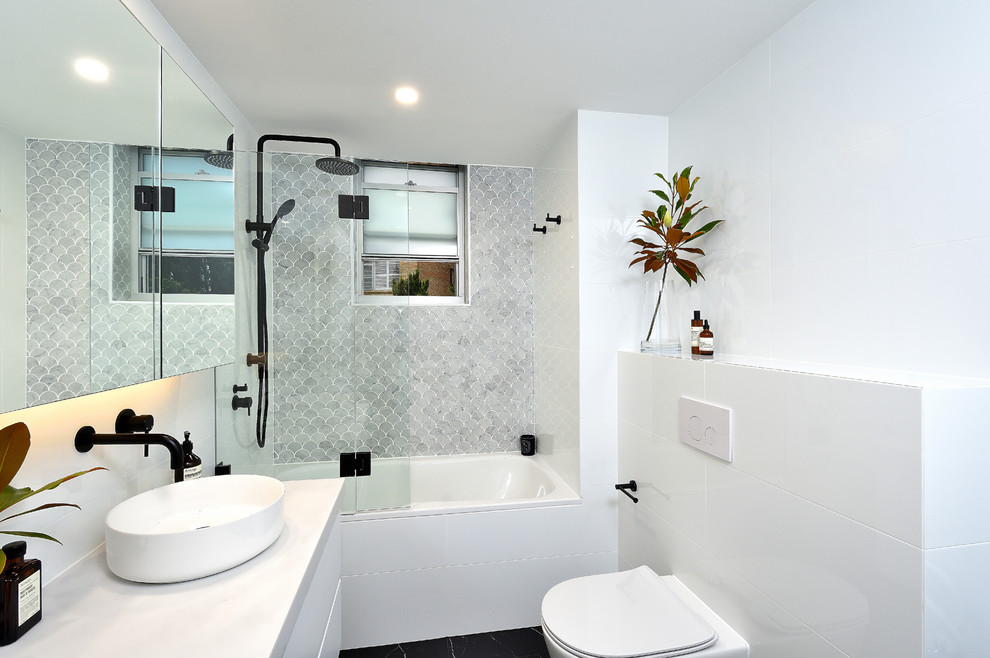 Источник вдохновения для домашнего уюта: маленькая главная ванная комната в стиле модернизм с стеклянными фасадами, белыми фасадами, ванной в нише, открытым душем, унитазом-моноблоком, белой плиткой, керамической плиткой, белыми стенами, полом из цементной плитки, настольной раковиной, столешницей из искусственного камня, черным полом, открытым душем и белой столешницей для на участке и в саду