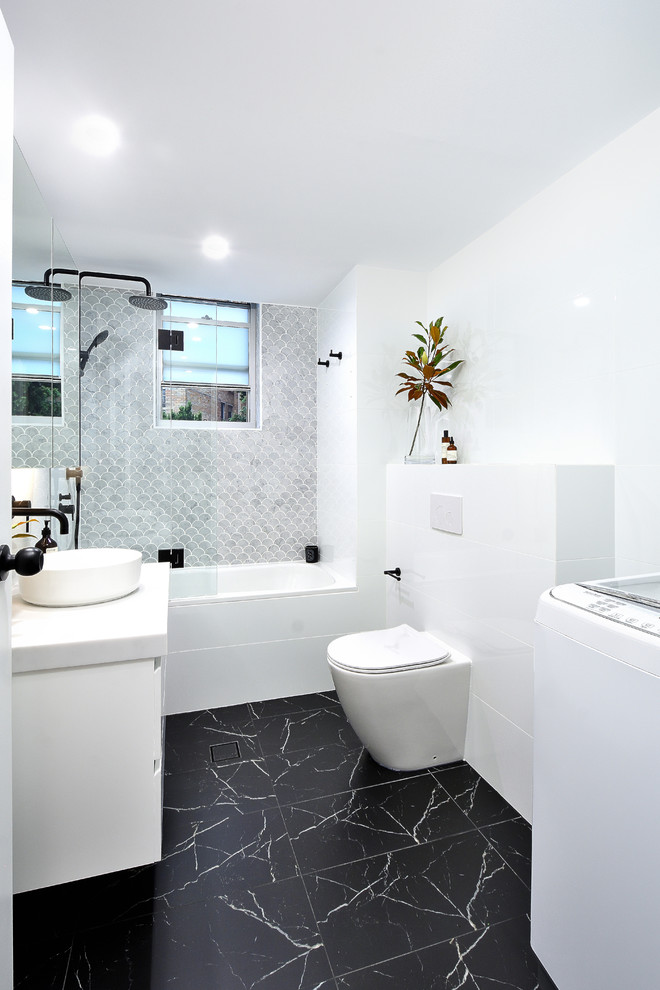 Свежая идея для дизайна: маленькая главная ванная комната в стиле модернизм с стеклянными фасадами, белыми фасадами, ванной в нише, открытым душем, унитазом-моноблоком, белой плиткой, керамической плиткой, белыми стенами, полом из цементной плитки, настольной раковиной, столешницей из искусственного камня, черным полом, открытым душем и белой столешницей для на участке и в саду - отличное фото интерьера