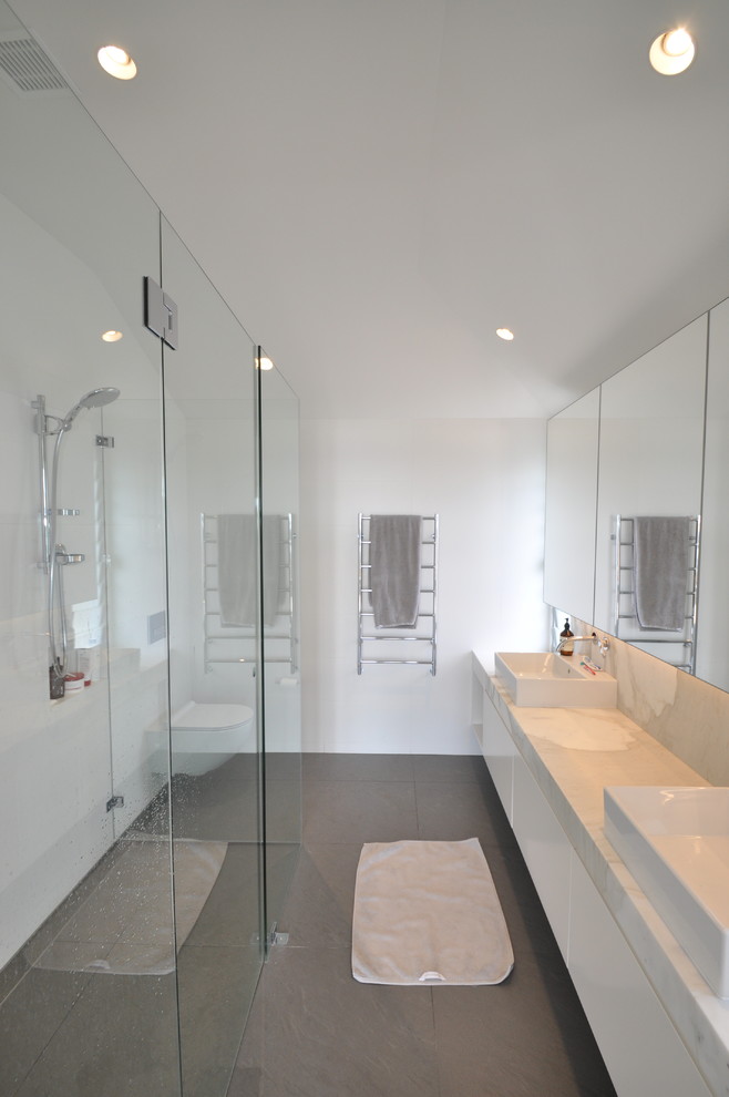 Idéer för ett mellanstort modernt badrum med dusch, med släta luckor, vita skåp, vit kakel, vita väggar, cementgolv, ett fristående handfat och marmorbänkskiva