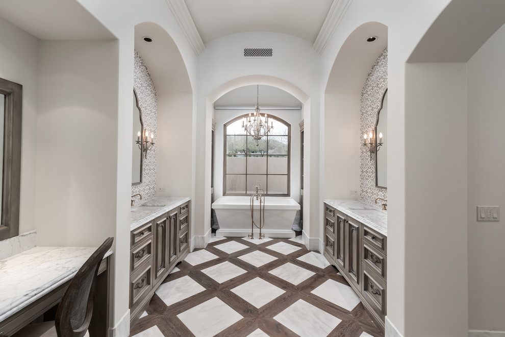 Modern inredning av ett mycket stort vit vitt en-suite badrum, med luckor med infälld panel, bruna skåp, ett fristående badkar, en dusch i en alkov, en toalettstol med separat cisternkåpa, flerfärgad kakel, porslinskakel, vita väggar, mellanmörkt trägolv, ett nedsänkt handfat, marmorbänkskiva, flerfärgat golv och dusch med gångjärnsdörr