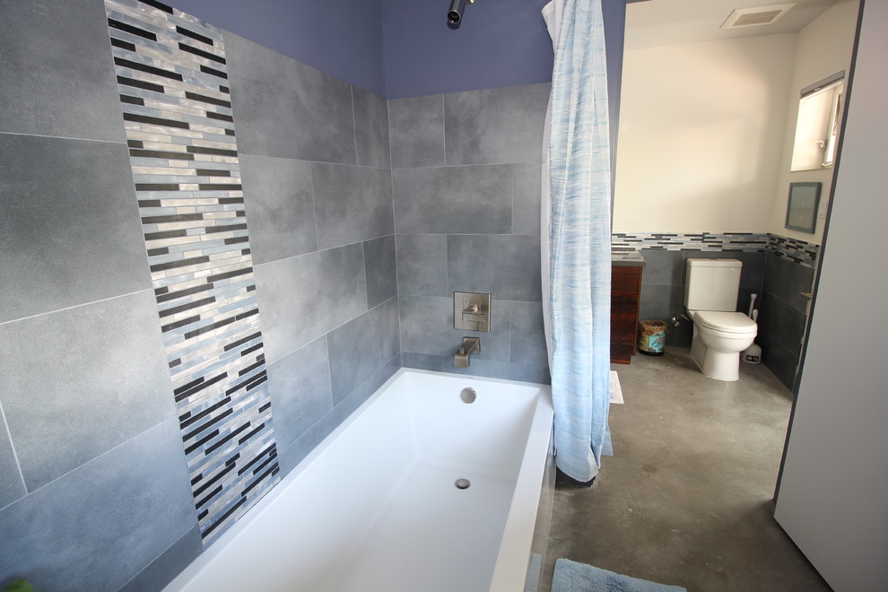 Modelo de cuarto de baño actual pequeño con bañera empotrada, combinación de ducha y bañera, sanitario de dos piezas, baldosas y/o azulejos de porcelana y suelo de cemento