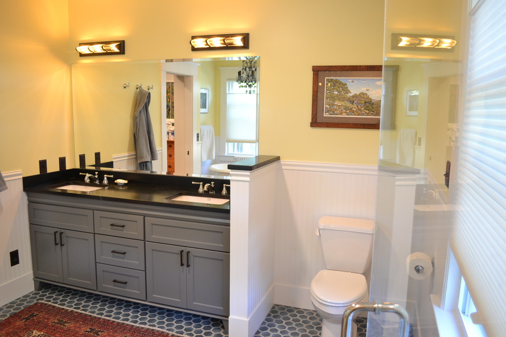 Foto di una stanza da bagno padronale stile americano di medie dimensioni con ante con riquadro incassato, ante grigie, WC a due pezzi, pareti gialle, pavimento con piastrelle in ceramica, lavabo sottopiano, pavimento grigio e top nero