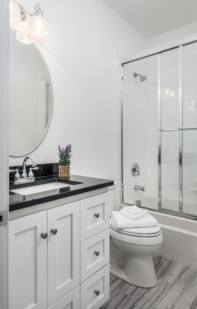 Esempio di una stanza da bagno american style con ante in stile shaker, ante bianche, vasca/doccia, porta doccia scorrevole e top nero