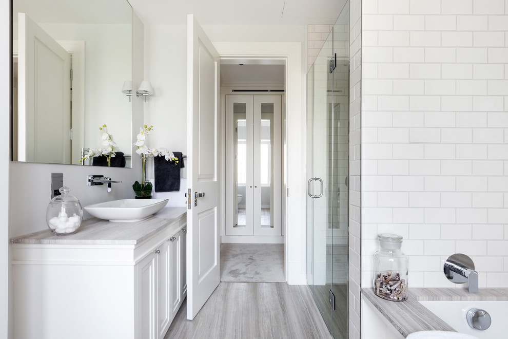 На фото: главная ванная комната в стиле неоклассика (современная классика) с фасадами с утопленной филенкой, белыми фасадами, полновстраиваемой ванной, белой плиткой, плиткой кабанчик, белыми стенами и настольной раковиной