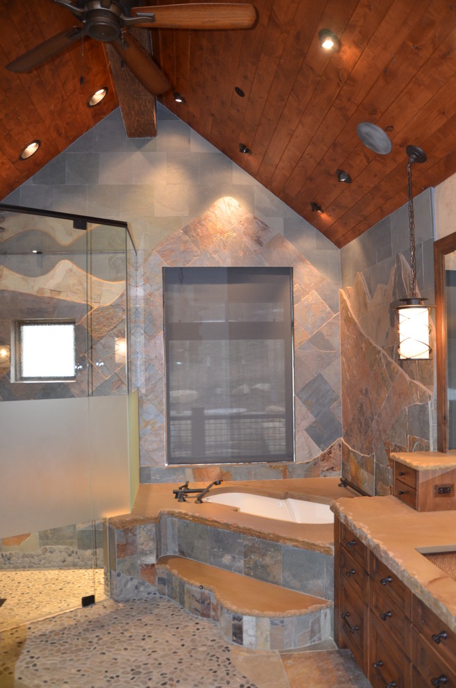Inspiration for a medium sized rustic ensuite bathroom in Denver with recessed-panel cabinets, medium wood cabinets, a built-in bath, a corner shower, a submerged sink, grey tiles, stone tiles, grey walls, slate flooring, concrete worktops, grey floors and a hinged door.