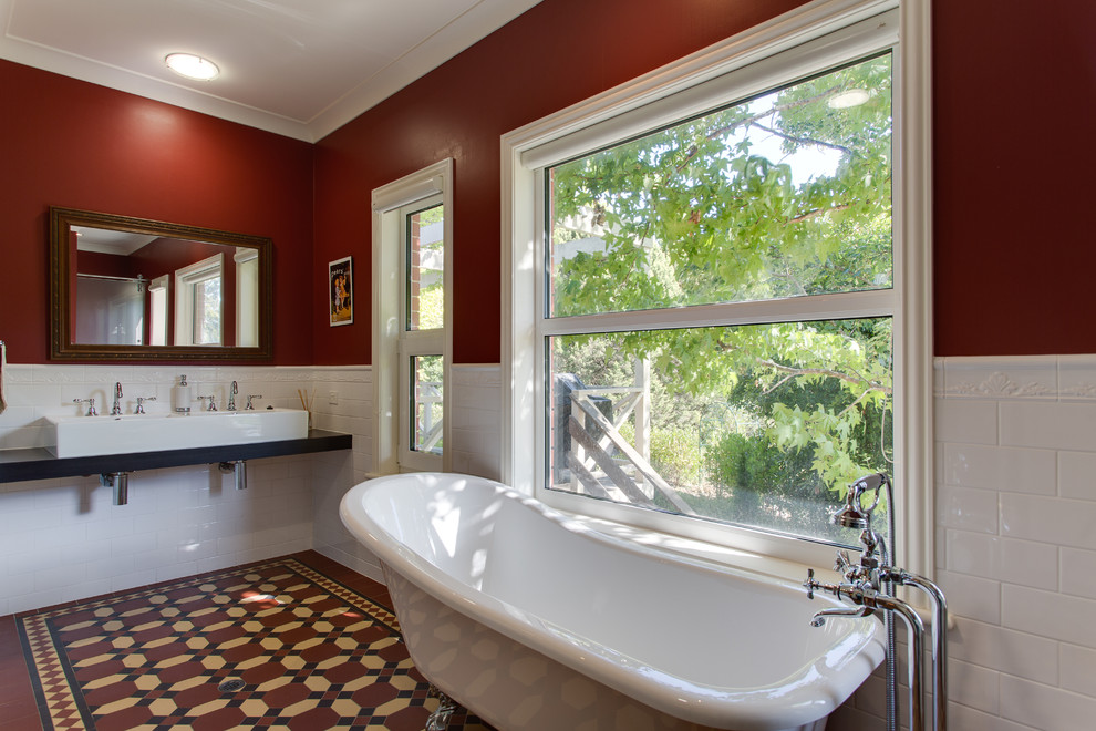 Foto på ett stort vintage en-suite badrum, med ett konsol handfat, släta luckor, laminatbänkskiva, ett badkar med tassar, en dubbeldusch, en toalettstol med hel cisternkåpa, röda väggar och klinkergolv i terrakotta