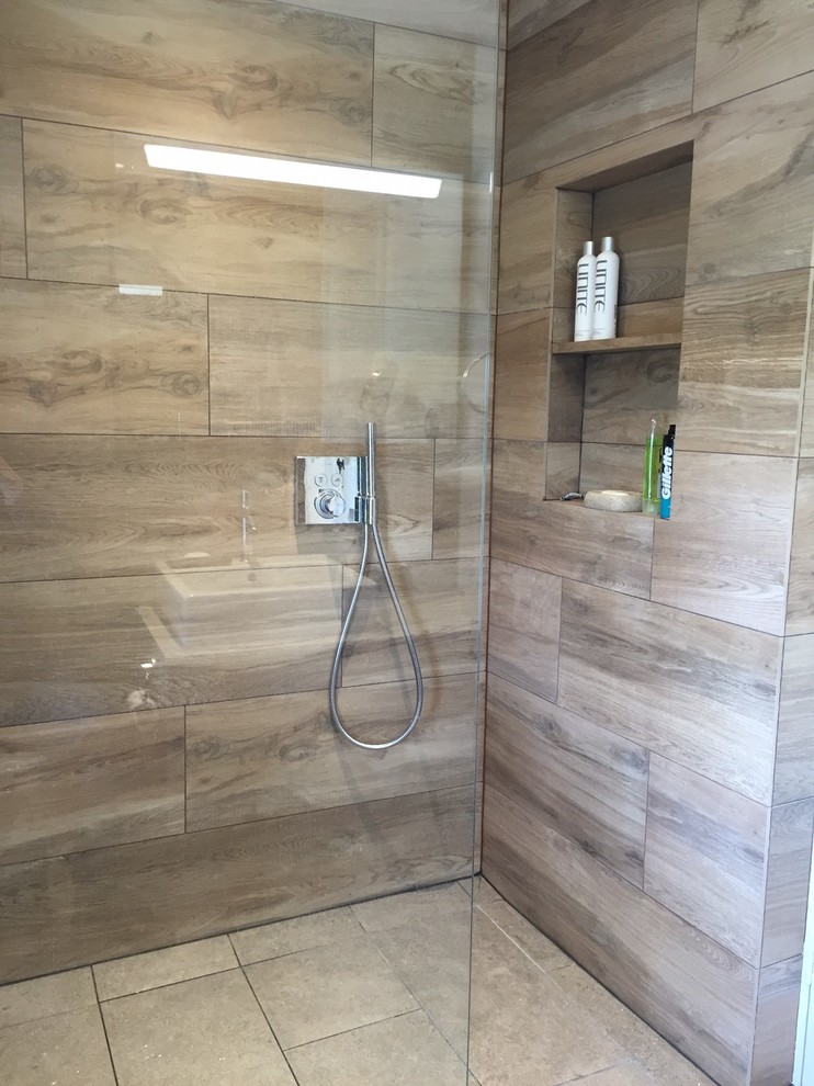 This is an example of a medium sized modern ensuite bathroom in Dorset with beige cabinets, solid surface worktops, a walk-in shower, beige tiles, porcelain tiles and porcelain flooring.