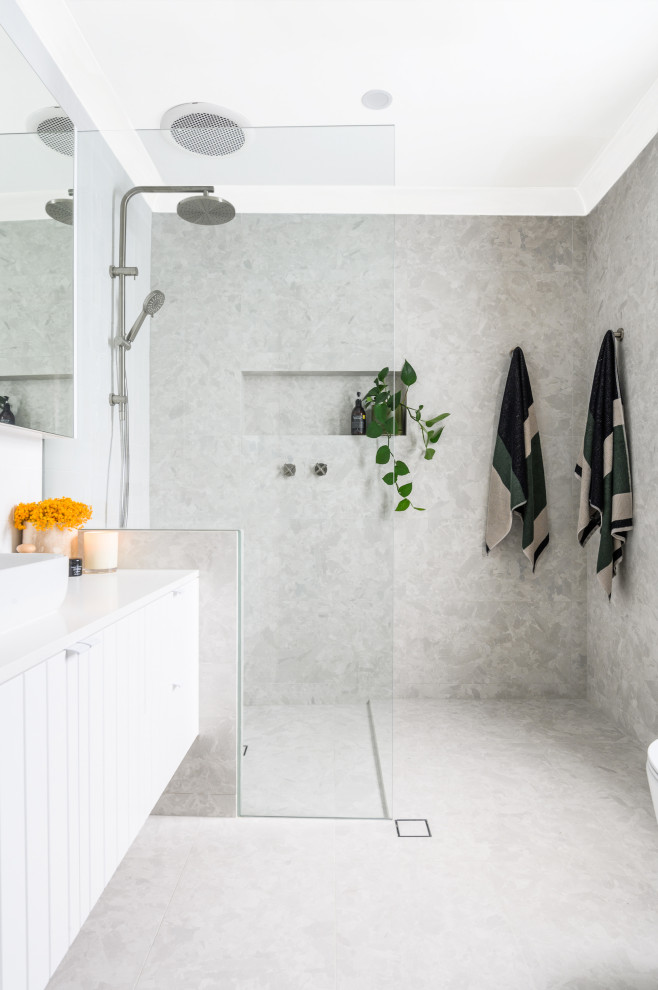 Idéer för stora funkis vitt badrum med dusch, med släta luckor, vita skåp, en öppen dusch, grå kakel, ett fristående handfat och grått golv