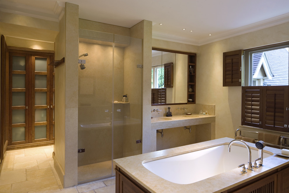 Foto på ett funkis badrum, med ett integrerad handfat, ett undermonterat badkar, en dusch i en alkov, beige kakel och stenkakel