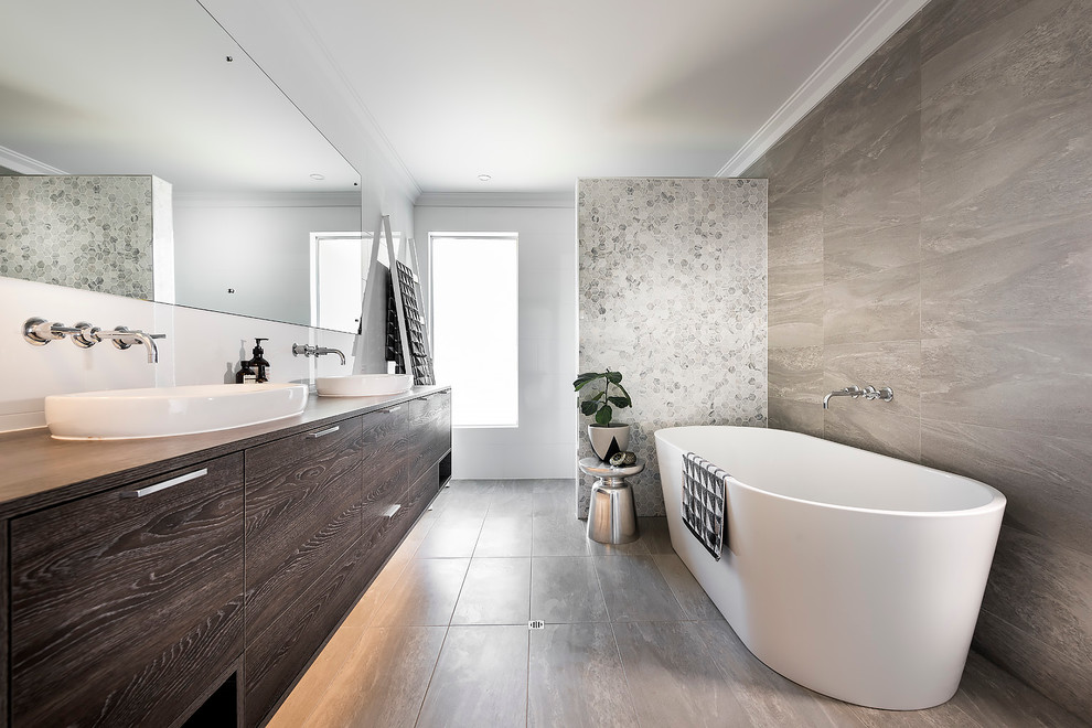 На фото: ванная комната в скандинавском стиле с плоскими фасадами, темными деревянными фасадами, отдельно стоящей ванной, белыми стенами и накладной раковиной