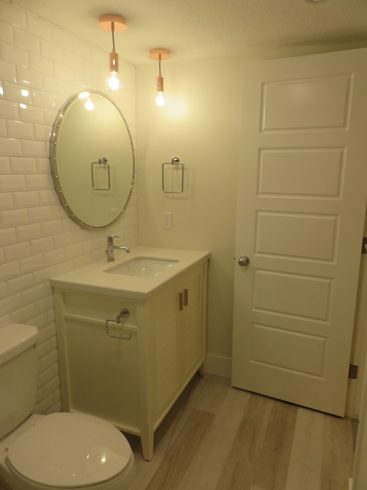 Пример оригинального дизайна: маленькая детская ванная комната в стиле неоклассика (современная классика) с фасадами с филенкой типа жалюзи, белыми фасадами, ванной в нише, раздельным унитазом, белой плиткой, плиткой кабанчик, белыми стенами, полом из керамической плитки, врезной раковиной, столешницей из кварцита и серым полом для на участке и в саду