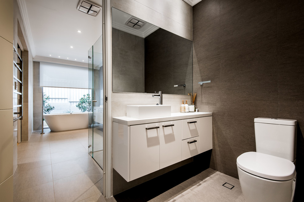 Imagen de cuarto de baño contemporáneo con armarios con paneles lisos, puertas de armario blancas, bañera exenta, sanitario de dos piezas, paredes marrones y lavabo sobreencimera