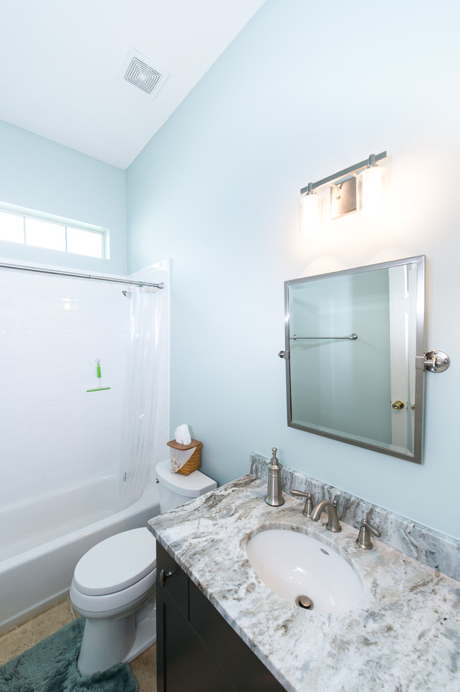 Modelo de cuarto de baño tradicional renovado con bañera encastrada, combinación de ducha y bañera, baldosas y/o azulejos blancos, baldosas y/o azulejos de cemento, paredes azules, lavabo bajoencimera y encimera de granito