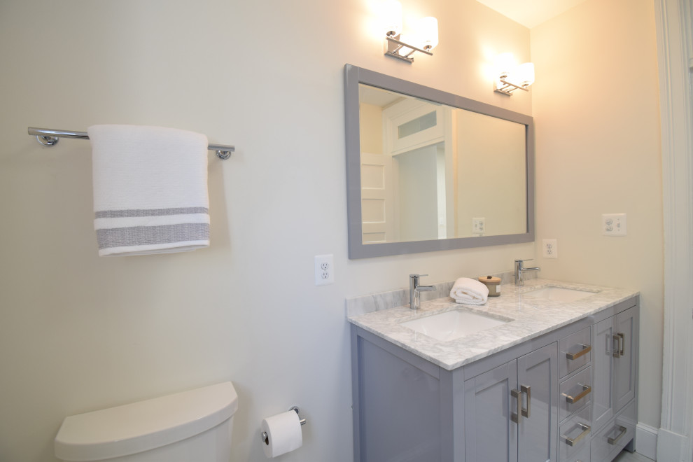 This is an example of a medium sized classic family bathroom in DC Metro with recessed-panel cabinets, grey cabinets, an alcove bath, a two-piece toilet, grey tiles, ceramic tiles, white walls, ceramic flooring, a submerged sink, marble worktops, grey floors and multi-coloured worktops.