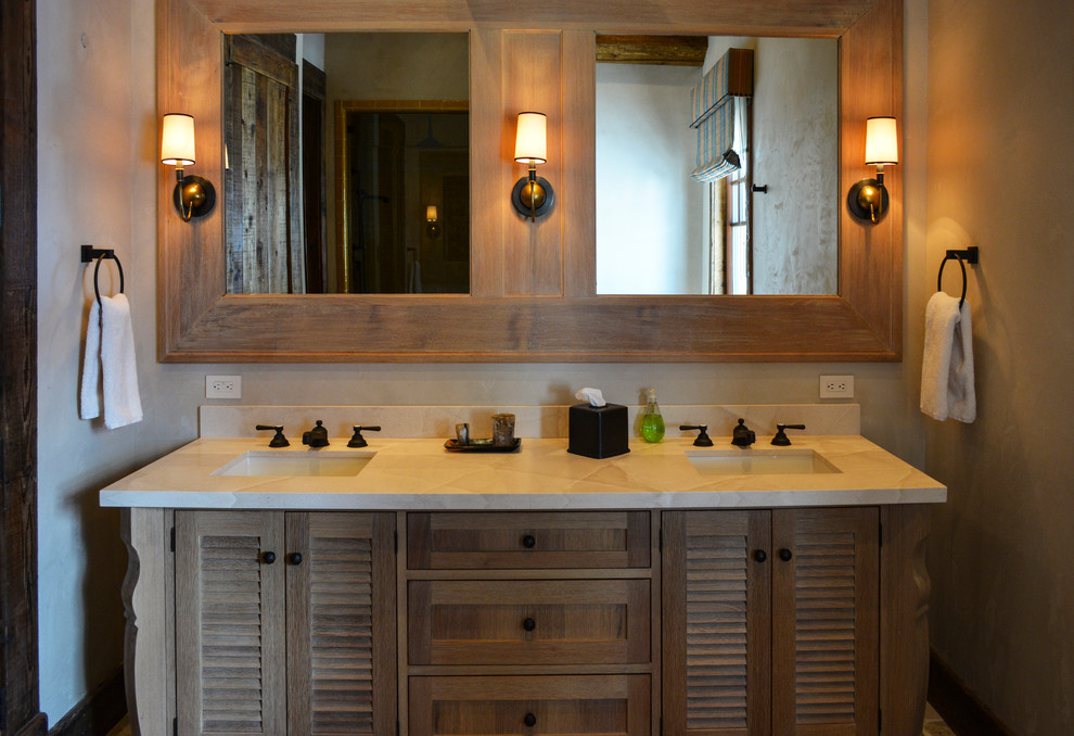 Стильный дизайн: ванная комната в стиле рустика с фасадами с филенкой типа жалюзи, светлыми деревянными фасадами, врезной раковиной и белой столешницей - последний тренд