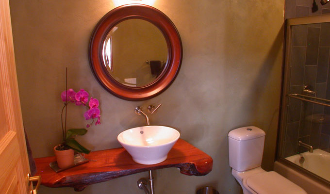 На фото: маленькая ванная комната в современном стиле с столешницей из дерева, серой плиткой, каменной плиткой, настольной раковиной, накладной ванной, душем над ванной, раздельным унитазом, зелеными стенами и полом из сланца для на участке и в саду